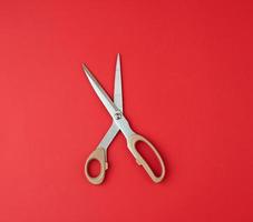 iron scissors with a beige plastic handle on a red background, top view photo