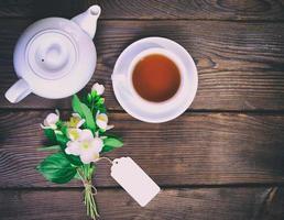 té negro en una taza blanca, junto a una cafetera blanca foto