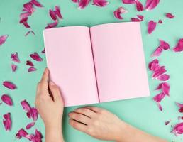 open notebook with empty pink pages and two female hands photo