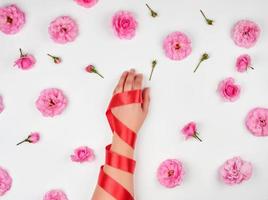 female hand with smooth skin wrapped with red silk ribbon photo