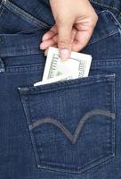 hand pulls out of the back pocket of blue jeans bill hundred dollars photo