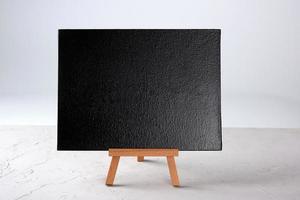 empty black frame stands on a wooden tripod photo