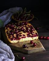 baked cake with cherries on a brown wooden board photo