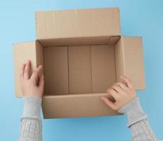 female hands are holding an empty open box of brown cardboard photo