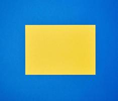 blank yellow sheet of A4 paper on a blue background photo