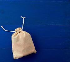pequeña bolsa de lona completa con lazos, fondo de madera azul foto