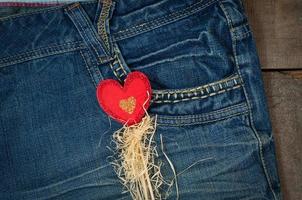 Wooden red heart on a stick on a background of blue worn jeans photo