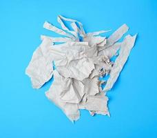 crumpled torn piece of gray paper on a blue background photo