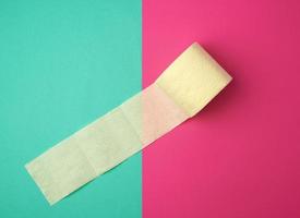 soft yellow toilet paper in a roll on a green-pink background photo