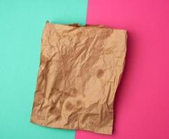 bolsa de papel marrón abierta para el envasado de alimentos con manchas grasientas sobre un fondo verde rosa foto
