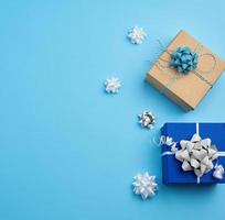 two square gift boxes decorated with ribbons and bows on a blue background photo