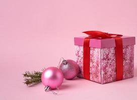 pink gift box with bow, green spruce branch and two decorative pink balls photo