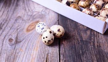 Three fresh quail eggs on a gray wooden surface photo