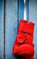 Red kickboxing glove hanging on a wooden blue surface photo