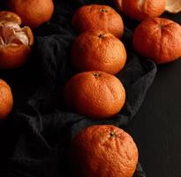 mandarina naranja madura sobre una mesa negra, frutas maduras y jugosas. comida sana vegetariana foto
