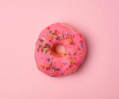 pink round donut with colored sprinkles photo