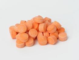 orange pills on white background, vitamin C, close up photo