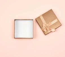 open golden square gift box with a bow on a beige background photo