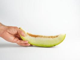 male hand holds a piece of ripe melon with seeds photo