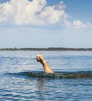 hand sticks out of the water and shows a gesture like photo