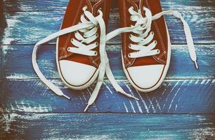 pair of red sneakers on a blue shabby wooden surface photo