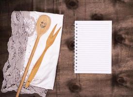 open notepad in a line and a wooden spoon with a fork photo