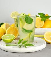 bebida refrescante limonada con limones, hojas de menta, lima en un vaso foto