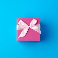 closed pink cardboard box with a bow on a blue background photo