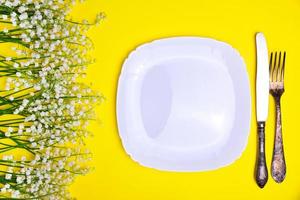 White plate and iron  cutlery on a yellow background photo