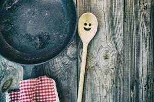 Black cast-iron frying pan with a wooden spatula photo