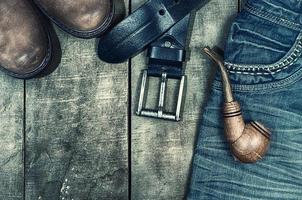 Detail of worn blue jeans and brown shoes on a wooden background photo