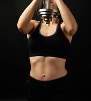 young woman of Caucasian appearance holds steel type-setting dumbbell photo