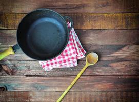 deep cast-iron frying pan with a wooden spoon, top view photo