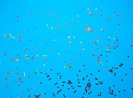shiny multicolored round confetti scattered on a blue background photo