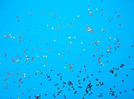 shiny multicolored round confetti scattered on a blue background photo