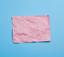 empty crumpled pink rectangular sheet of paper a4 on a blue background photo