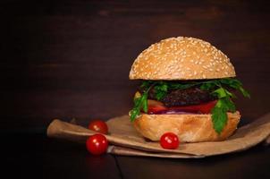 hamburguesa casera con chuleta de carne y verduras servidas en un papel foto