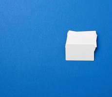 pila de tarjetas de visita rectangulares blancas en blanco sobre un fondo azul foto