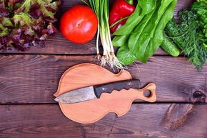 Fresh vegetables and a cutting board with a knife photo