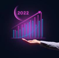 Holographic graph with growing indicators and a businessman's hand. The concept of business growth in the new year, the beginning of success photo