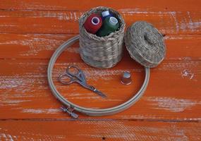 Spools of thread in a wicker basket and items for needlework photo