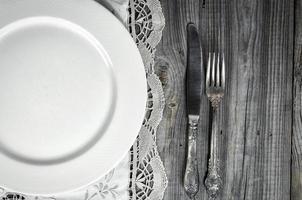 White empty plate on the tablecloth with lace, near knife and fork photo
