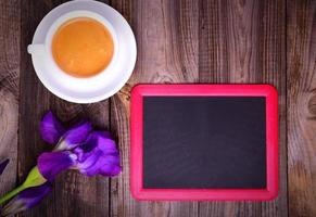 Empty black chalk board with a cup of coffee on a gray surface photo