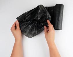 blue plastic garbage bag in female hands on a white background photo