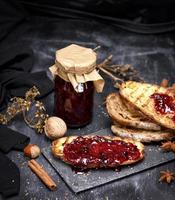 tostadas de pan blanco con mermelada de frambuesa y un tarro de cristal con mermelada foto