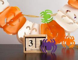 wooden calendar of cubes, garland of pumpkins and spiders photo