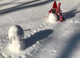 pequeña muñeca de madera en la escena de la construcción de un muñeco de nieve foto