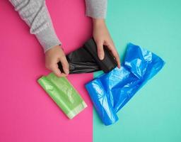 female hand unwinds a black plastic bag for rubbish photo