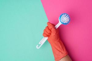 white plastic cleaning brush in hand, protective orange glove on hand photo