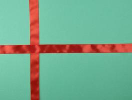 red satin ribbon cross to cross on green background photo